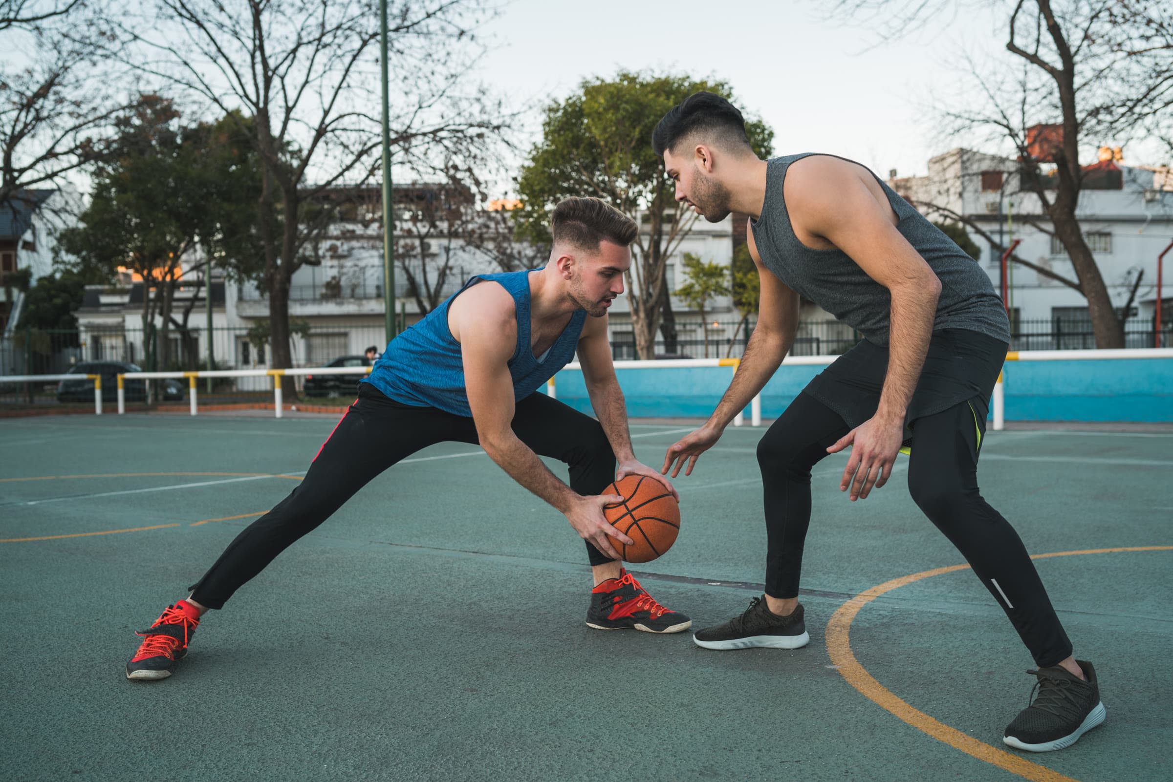 Two athletes facing off in a one-on-one basketball game on an outdoor court